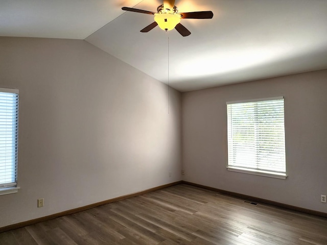 spare room featuring plenty of natural light, ceiling fan, wood finished floors, vaulted ceiling, and baseboards