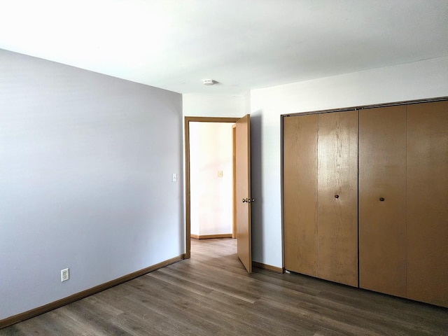 unfurnished bedroom with wood finished floors, a closet, and baseboards