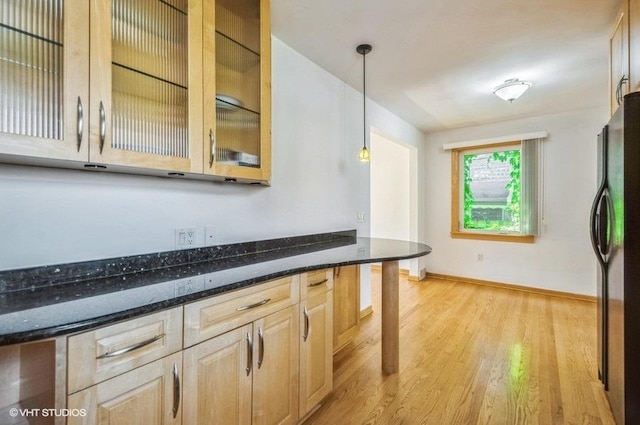 5116 N New England Ave, Chicago, IL 60656 - kitchen featuring freestanding refrigerator, light wood-style floors, dark stone countertops, decorative light fixtures, and glass insert cabinets