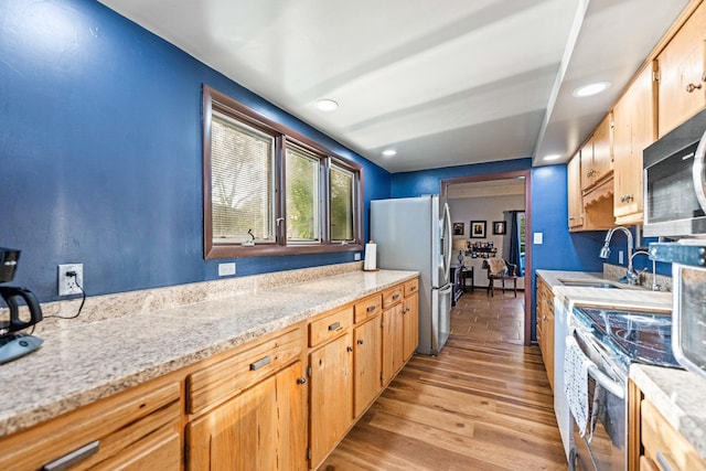 kitchen with stainless steel appliances, light wood-style flooring, recessed lighting, and a sink
