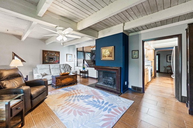 living area with a ceiling fan, visible vents, stairs, wood finished floors, and beam ceiling