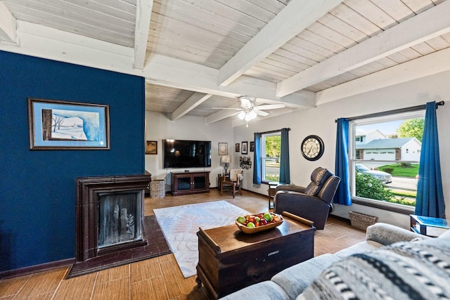 living area featuring wood ceiling, beamed ceiling, baseboards, and a healthy amount of sunlight