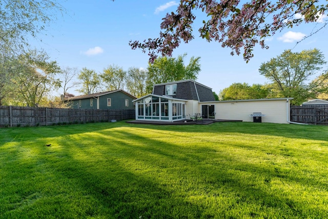 back of house featuring a sunroom, a lawn, and a fenced backyard