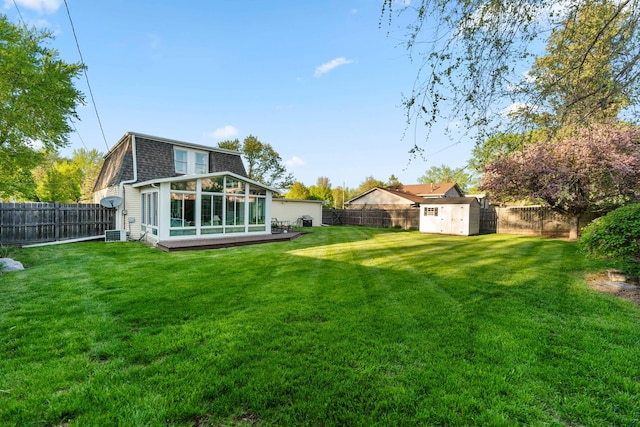 back of house featuring a sunroom, a fenced backyard, and a shed