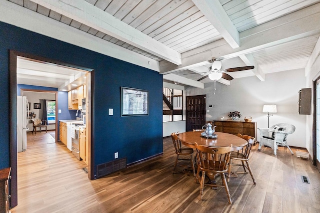 dining area with a ceiling fan, baseboards, visible vents, beamed ceiling, and light wood-type flooring
