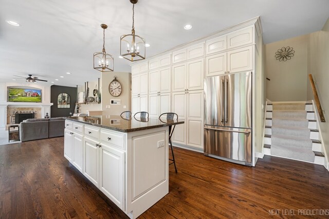 2401 Legacy Dr, Aurora, IL 60502 - kitchen featuring stainless steel refrigerator, a center island, a ceiling fan, dark wood-style floors, and a kitchen bar