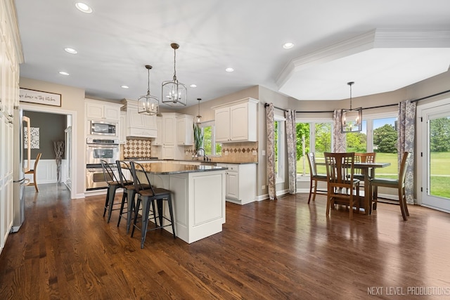 2401 Legacy Dr, Aurora, IL 60502 - kitchen featuring a chandelier, stainless steel appliances, white cabinets, a kitchen island, and a kitchen bar