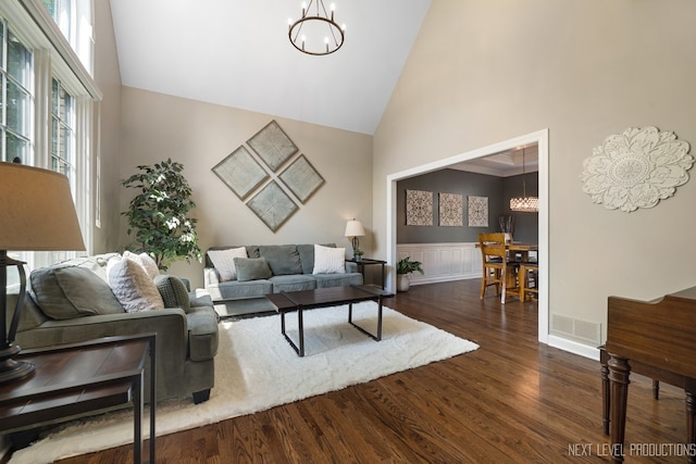 2401 Legacy Dr, Aurora, IL 60502 - living area with a chandelier, high vaulted ceiling, dark wood-style flooring, healthy amount of natural light, and a wainscoted wall