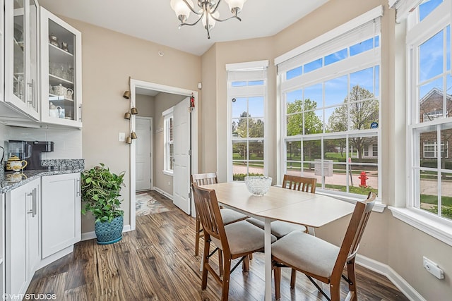 dining room featuring a chandelier, dark wood finished floors, and baseboards