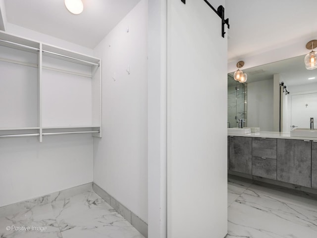 spacious closet featuring a barn door, marble finish floor, and a sink
