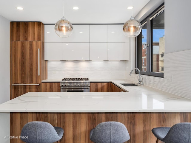 kitchen featuring a sink, high end range, white cabinetry, and modern cabinets