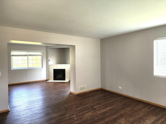 unfurnished living room with dark wood-style floors, baseboards, and a fireplace