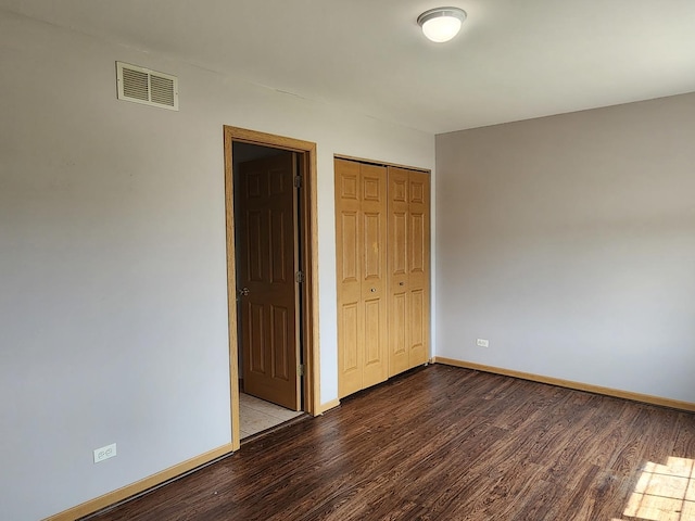 unfurnished bedroom featuring wood finished floors, baseboards, and a closet