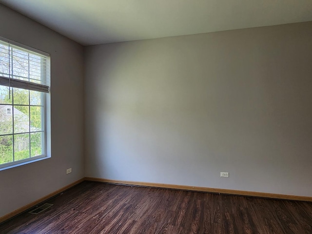 spare room featuring dark wood-style flooring and baseboards