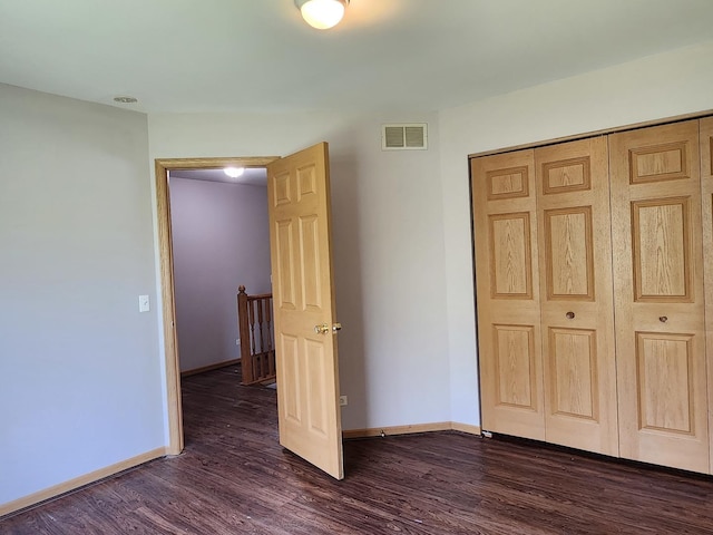 unfurnished bedroom featuring dark wood-type flooring, baseboards, and a closet
