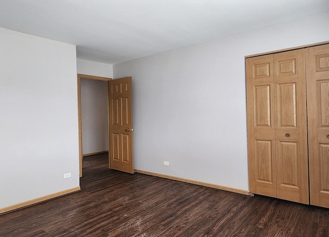 empty room with dark wood-type flooring and baseboards