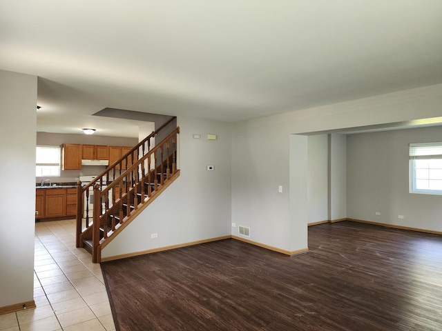 spare room with stairway, light wood-style floors, and baseboards