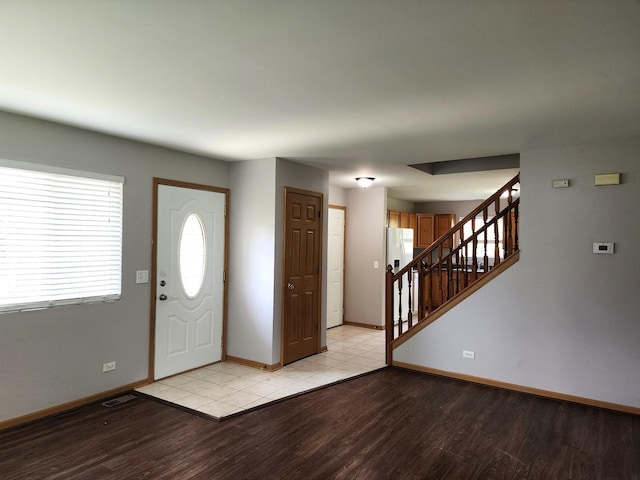 foyer featuring light wood-style flooring, baseboards, and stairway
