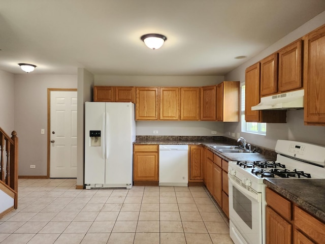 kitchen featuring white appliances, under cabinet range hood, a sink, dark countertops, and light tile patterned flooring