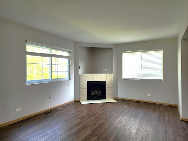 unfurnished living room with dark wood-type flooring, baseboards, and a fireplace