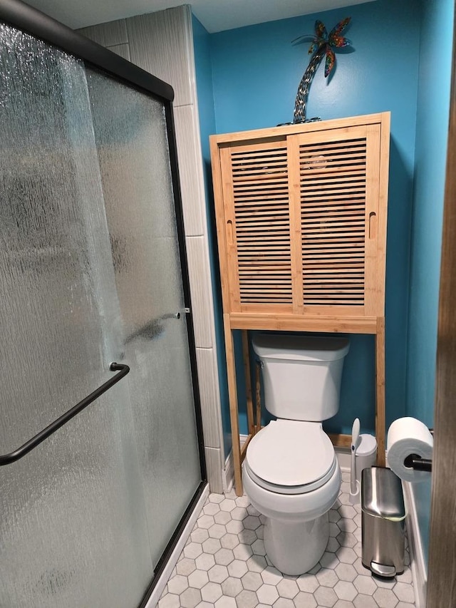 bathroom with toilet, tile patterned floors, and a shower stall