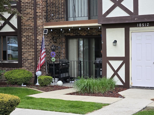 doorway to property with stucco siding, brick siding, and a balcony