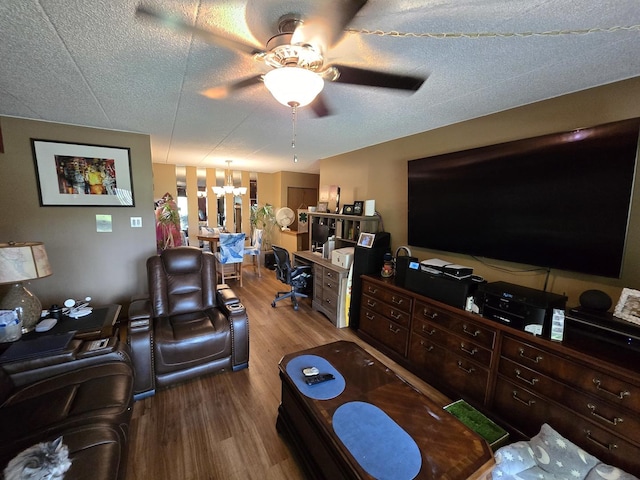 living room featuring ceiling fan with notable chandelier, a textured ceiling, and wood finished floors