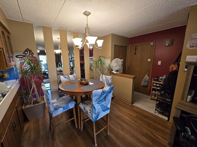 dining area with a textured ceiling, a notable chandelier, and wood finished floors