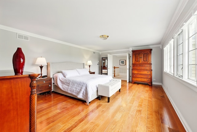 bedroom with light wood-style floors, ornamental molding, and baseboards