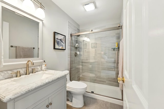 bathroom featuring a stall shower, toilet, vanity, and tile patterned flooring
