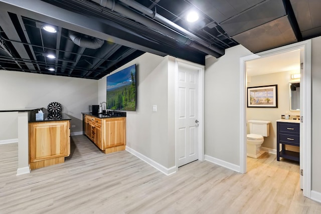 finished basement featuring light wood-style floors, baseboards, and a sink