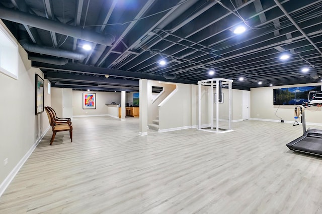 finished below grade area featuring wood finished floors, baseboards, and stairway