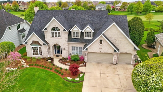 traditional home with concrete driveway, brick siding, roof with shingles, a front yard, and a residential view