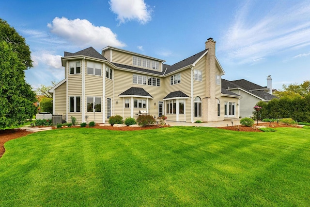 back of house with a patio area, a yard, a chimney, and central air condition unit