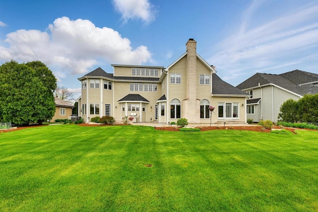rear view of house with a chimney, a patio, and a yard