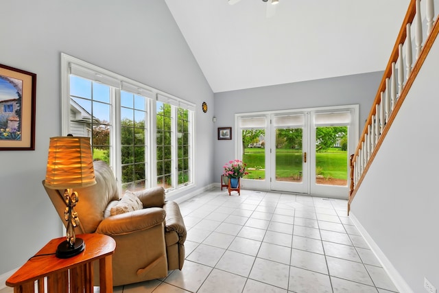 living area with high vaulted ceiling, stairs, light tile patterned floors, and plenty of natural light