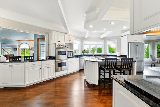 kitchen with stainless steel appliances, recessed lighting, dark wood-style floors, a breakfast bar, and plenty of natural light