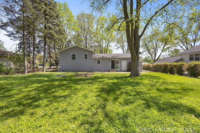 back of property with a yard and central AC