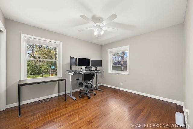home office with healthy amount of natural light, wood finished floors, ceiling fan, and baseboards