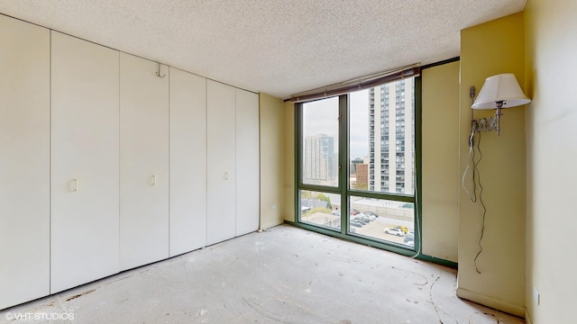 111 W Maple St Unit 1001, Chicago, IL 60610 - unfurnished bedroom with a textured ceiling, expansive windows, a closet, a city view, and unfinished concrete floors