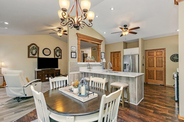 dining area featuring dark wood finished floors, lofted ceiling, ceiling fan with notable chandelier, and recessed lighting