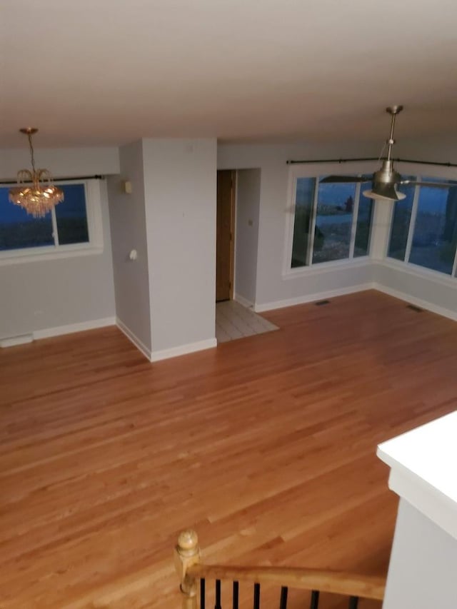 5849 Emerson St, Morton Grove, IL 60053 - unfurnished living room with light wood finished floors, a notable chandelier, and baseboards