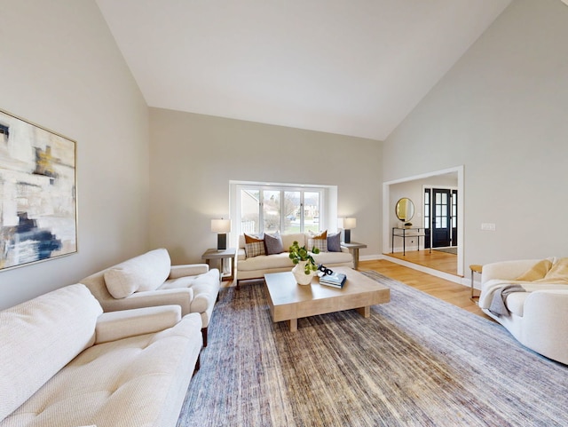 living area with wood finished floors, baseboards, and high vaulted ceiling