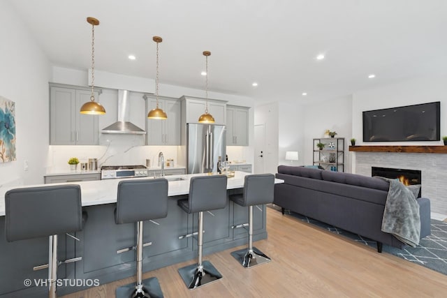 847 W Ainslie St Unit 2E, Chicago, IL 60640 - kitchen with high quality fridge, light countertops, wall chimney range hood, and light wood-style floors