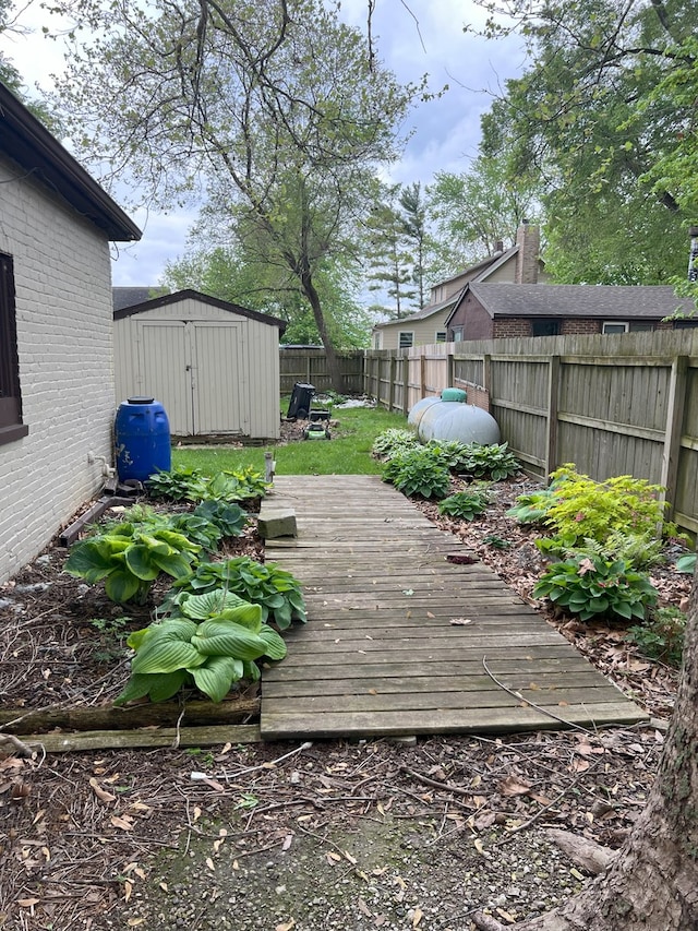 wooden terrace with an outbuilding, a fenced backyard, and a storage unit