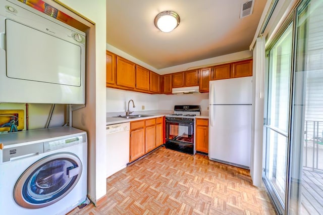 kitchen featuring stacked washer and clothes dryer, a sink, white appliances, under cabinet range hood, and light countertops