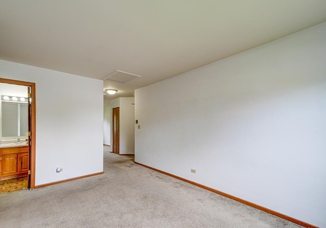 unfurnished room featuring baseboards, light carpet, and a sink