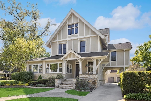 tudor house with concrete driveway, covered porch, stucco siding, a shingled roof, and a carport