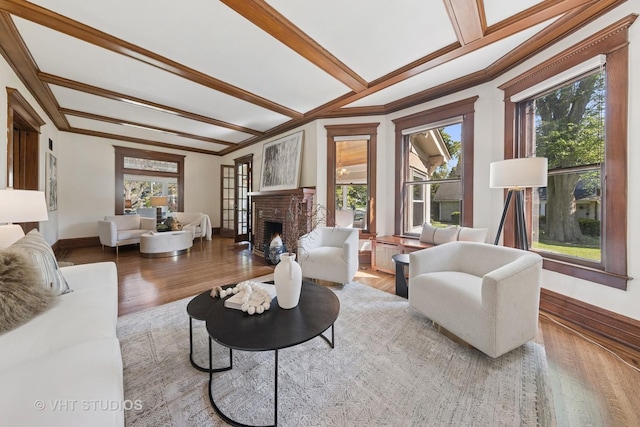 living room featuring plenty of natural light, crown molding, a fireplace, baseboards, and wood finished floors