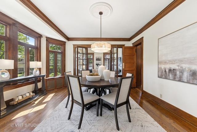 dining room with wood finished floors, crown molding, and baseboards